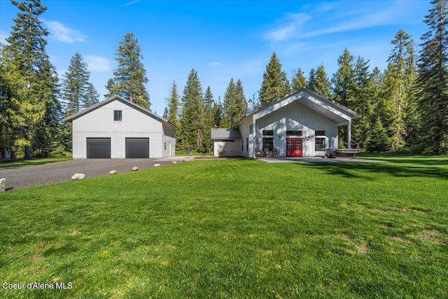 view of grassy yard featuring a detached garage and an outbuilding
