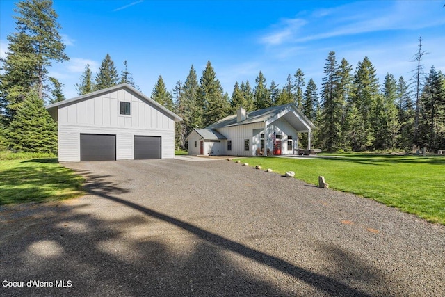 view of side of home with board and batten siding, an outdoor structure, a lawn, and a garage
