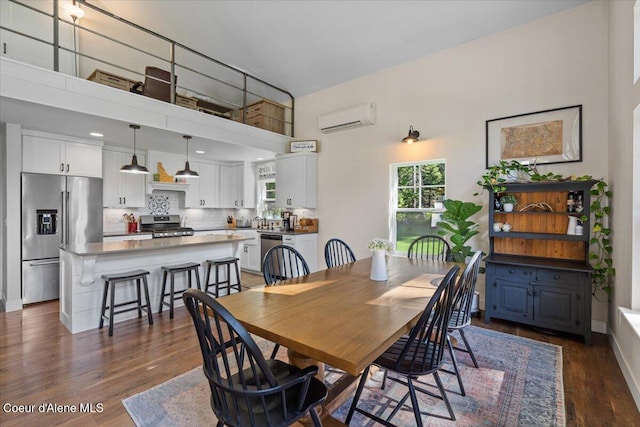 dining area with a wall unit AC, dark wood-style flooring, and a towering ceiling
