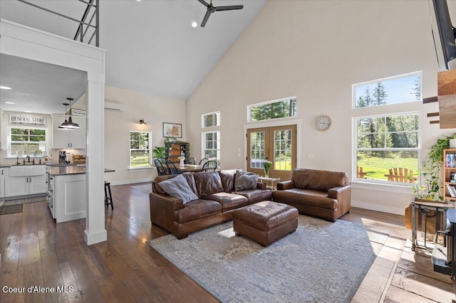living area featuring high vaulted ceiling, a ceiling fan, dark wood-style flooring, baseboards, and an AC wall unit