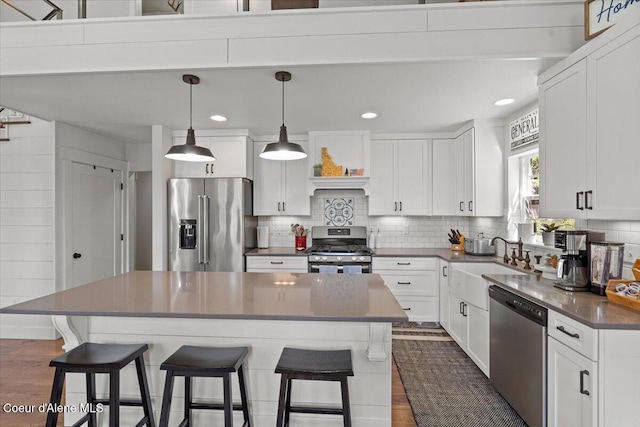 kitchen with stainless steel appliances, a sink, a kitchen breakfast bar, tasteful backsplash, and recessed lighting