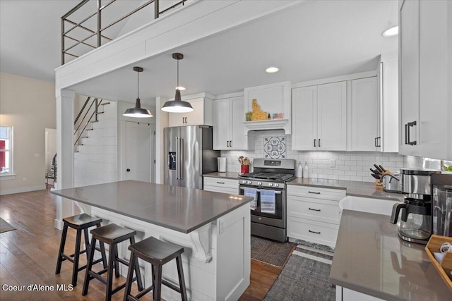 kitchen with stainless steel appliances, dark countertops, white cabinets, tasteful backsplash, and recessed lighting