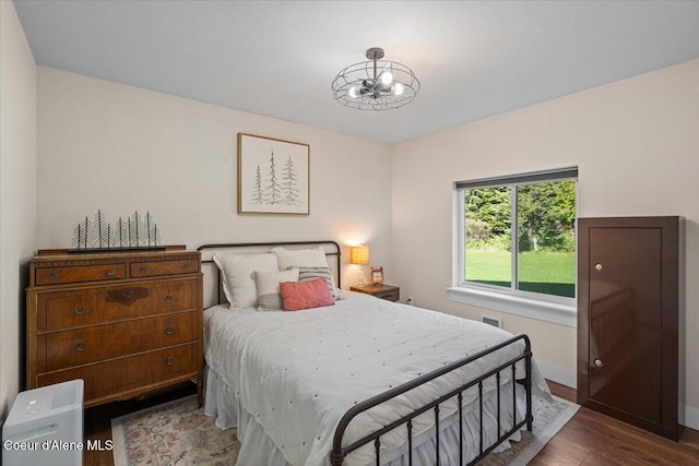 bedroom featuring wood finished floors, baseboards, and a chandelier