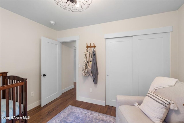bedroom with wood finished floors, baseboards, and a closet