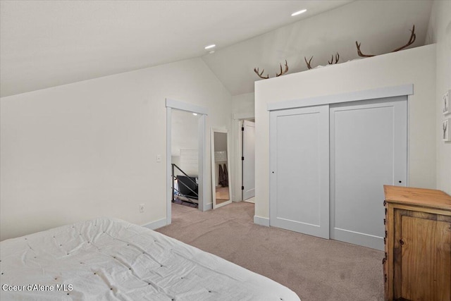 bedroom featuring light carpet, lofted ceiling, a closet, baseboards, and connected bathroom