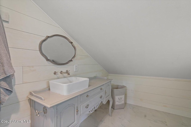 bathroom with marble look tile flooring, vanity, a wainscoted wall, and wood walls