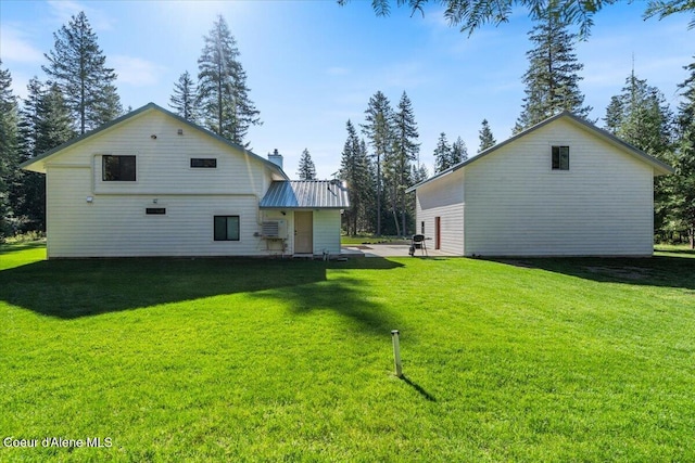 back of house with a lawn, a chimney, and metal roof