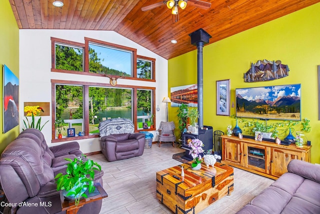 living area featuring a wood stove, healthy amount of natural light, ceiling fan, wood ceiling, and wood finished floors