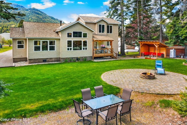 rear view of house featuring a fire pit, a patio area, a deck with mountain view, a lawn, and outdoor dining space