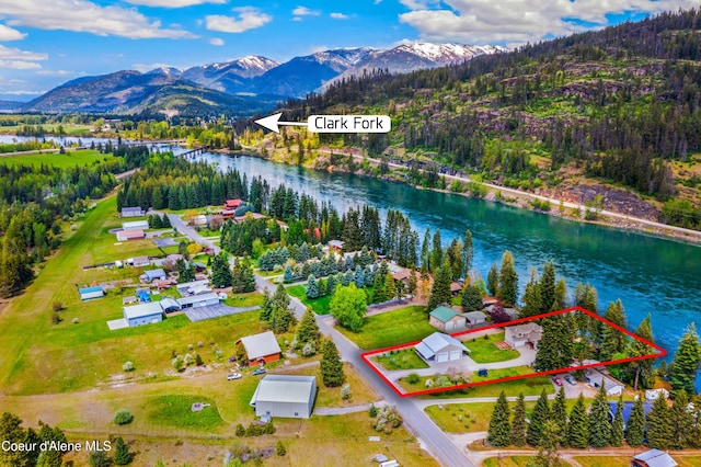 aerial view of property and surrounding area with a water and mountain view, property parcel outlined, and a heavily wooded area