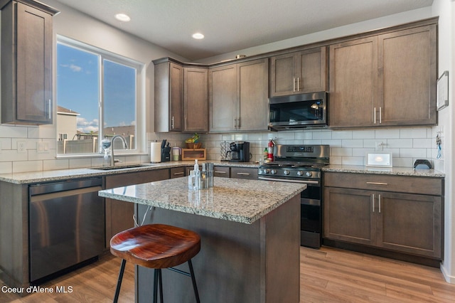 1749 N Minam Loop, Post Falls, ID 83854 - kitchen with stainless steel appliances, a sink, tasteful backsplash, a kitchen bar, and light wood-style flooring