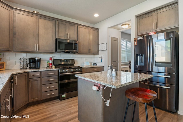 1749 N Minam Loop, Post Falls, ID 83854 - kitchen with appliances with stainless steel finishes, light wood-style flooring, light stone countertops, decorative backsplash, and recessed lighting