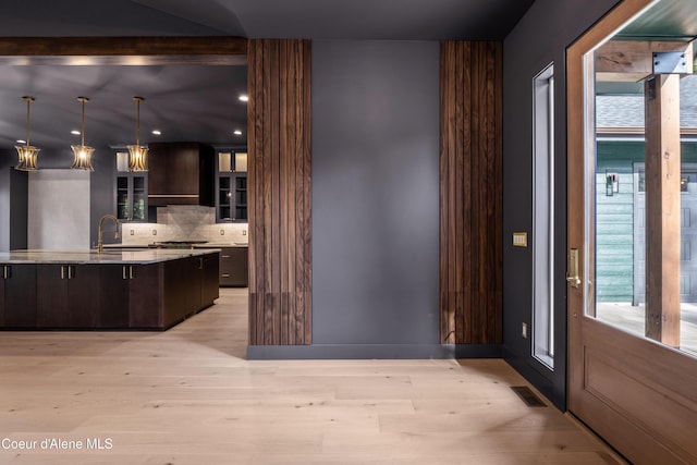 kitchen featuring dark brown cabinetry, tasteful backsplash, light wood-style floors, healthy amount of natural light, and recessed lighting