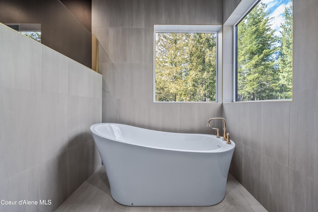 full bathroom with tile walls and a freestanding bath