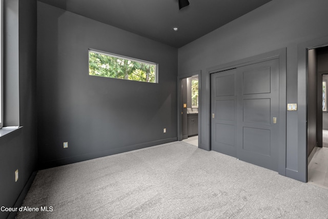 unfurnished bedroom with carpet floors, a closet, and ensuite bathroom