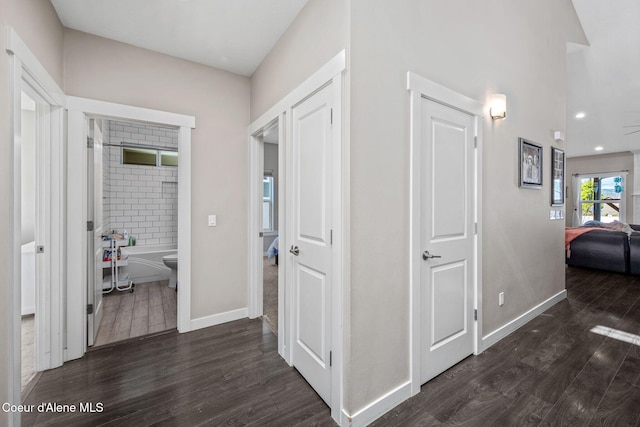 hall featuring dark wood finished floors, baseboards, and recessed lighting