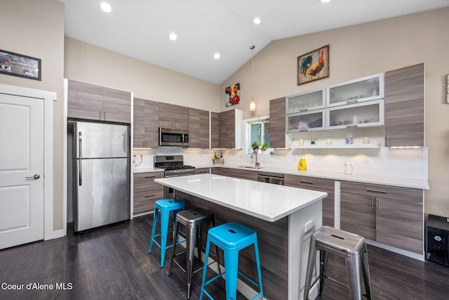 kitchen with stainless steel appliances, a kitchen bar, a sink, dark wood-style flooring, and a center island