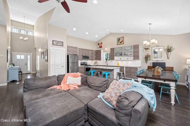 living room featuring a chandelier, high vaulted ceiling, dark wood-type flooring, baseboards, and a ceiling fan