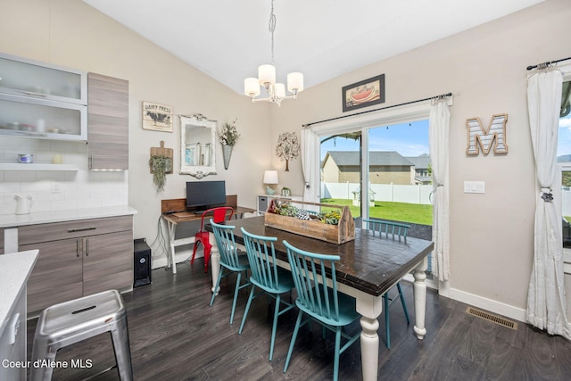 dining area with dark wood-style floors, a chandelier, baseboards, and vaulted ceiling