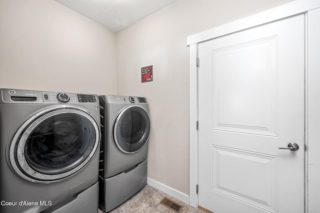 washroom featuring separate washer and dryer, baseboards, and a textured ceiling