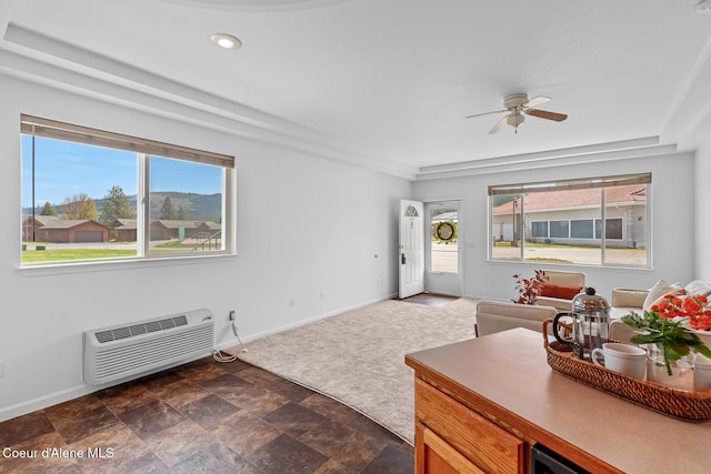living room with ceiling fan, baseboards, and a wall mounted AC