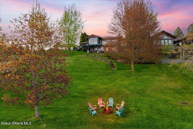view of green lawn featuring an outdoor fire pit and stairway