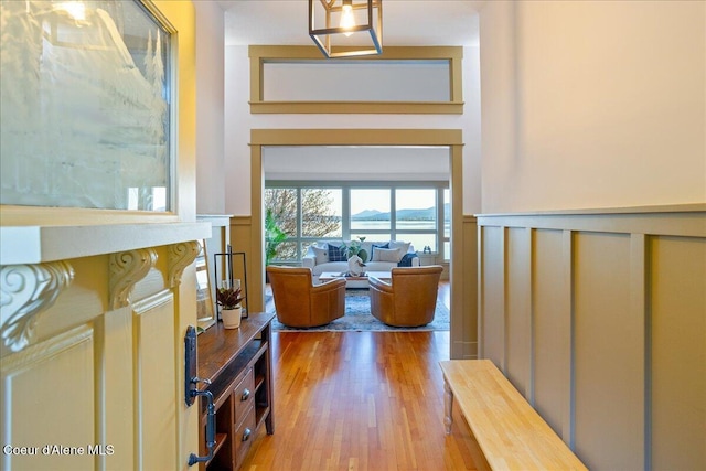 corridor with wood finished floors and a wainscoted wall
