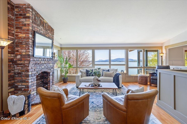 living area with light wood-type flooring, healthy amount of natural light, and a fireplace