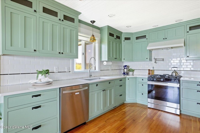 kitchen with appliances with stainless steel finishes, under cabinet range hood, green cabinets, a sink, and wood ceiling