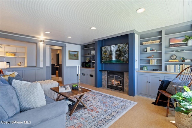 living area featuring built in features, light colored carpet, wainscoting, recessed lighting, and a tiled fireplace
