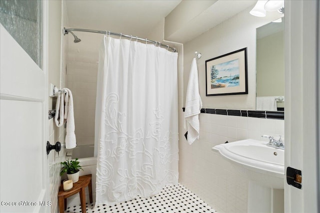 bathroom featuring tile walls, shower / tub combo, tile patterned flooring, and wainscoting
