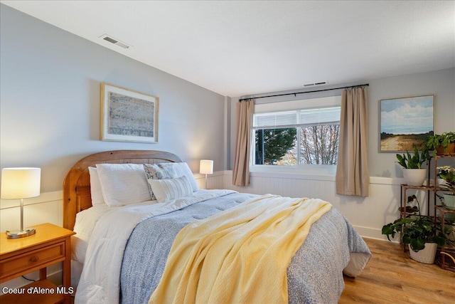 bedroom with wood finished floors and a wainscoted wall