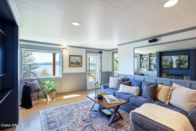 living room featuring wainscoting, a decorative wall, crown molding, and recessed lighting