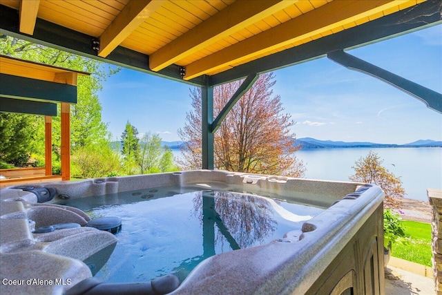 deck with a hot tub and a water view