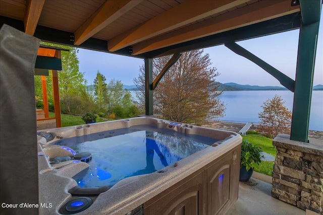 view of swimming pool featuring a hot tub and a water view