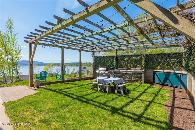 view of green lawn featuring a water view and a pergola