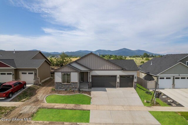 1451 W Tali Ave, Post Falls, ID 83854 - view of front of home with stone siding, a mountain view, a garage, and board and batten siding