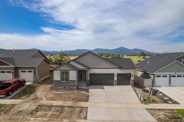 1451 W Tali Ave, Post Falls, ID 83854 - view of front of house with a mountain view, stone siding, an attached garage, board and batten siding, and concrete driveway