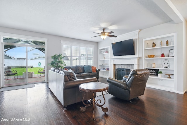 1823 N Clark Fork Pkwy, Post Falls, ID 83854 - living room featuring ceiling fan, dark wood-type flooring, a textured ceiling, a fireplace, and built in shelves