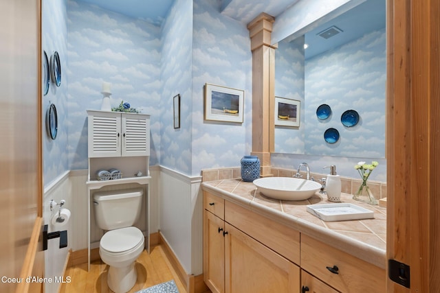 679 Comeback Bay Ln, Sagle, ID 83860 - bathroom with toilet, a wainscoted wall, vanity, wood finished floors, and wallpapered walls