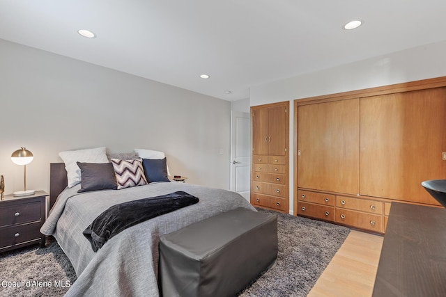 bedroom with wood finished floors, recessed lighting, and multiple closets