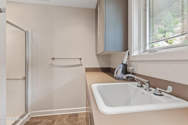 bathroom featuring a sink, a shower stall, and baseboards