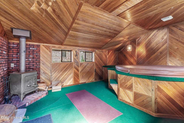 interior space with carpet, a wood stove, wood walls, wood ceiling, and lofted ceiling