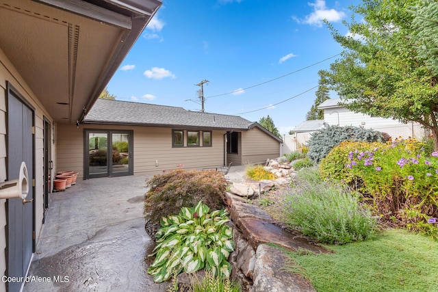rear view of property with a patio and roof with shingles