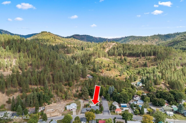 aerial view of property and surrounding area featuring a forest and mountains