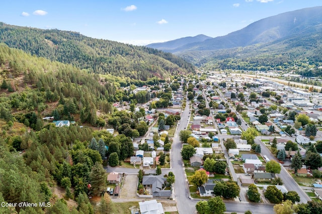 aerial view of property and surrounding area with a mountain backdrop, a forest, and nearby suburban area
