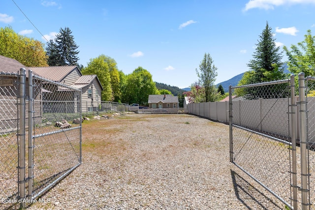 view of yard with fence, a mountain view, and a gate