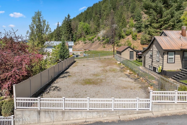 fenced yard with a forest view