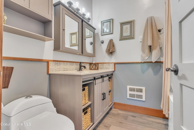 3226 District Two Rd, Bonners Ferry, ID 83805 - full bathroom with heating unit, baseboards, toilet, vanity, and wood finished floors
