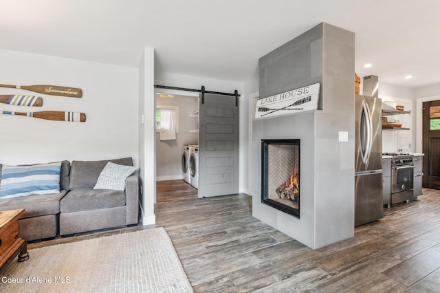 130 Cedar Shls, Sagle, ID 83860 - living area with washer and clothes dryer, a barn door, wood finished floors, a warm lit fireplace, and recessed lighting